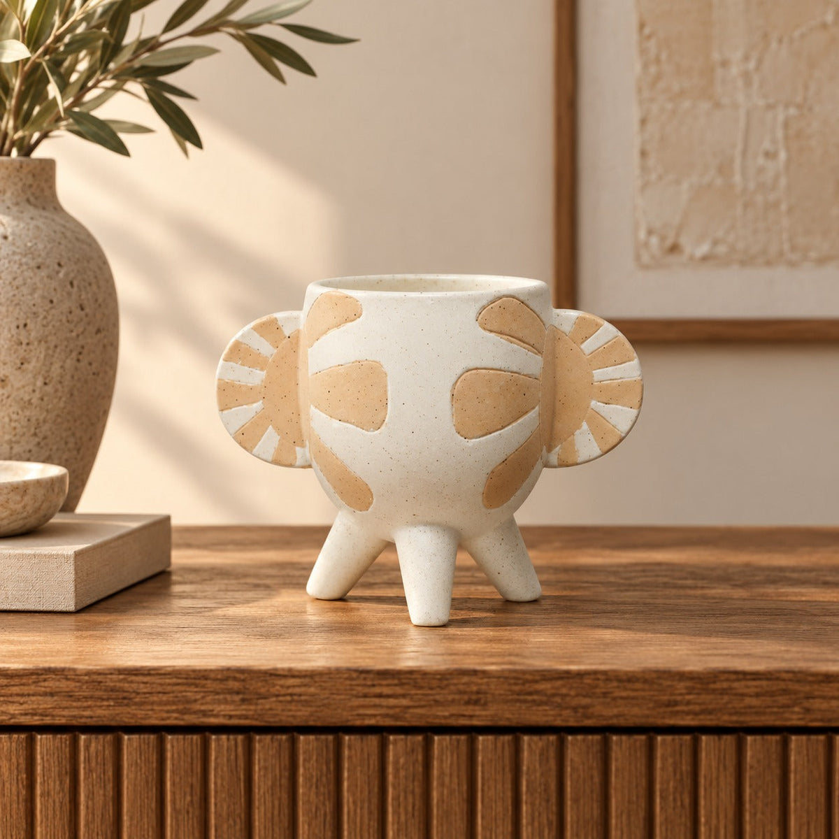 Leather Gallery Levante Decorative Vase, featuring a speckled off-white ceramic elephant design with raised tan detailing on a wooden console table.