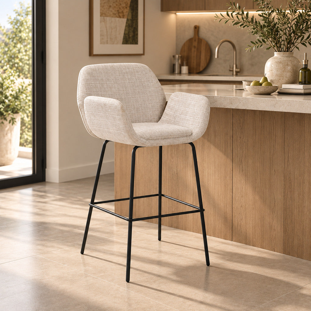 Gallery Everyday Arlo Bar Chair in Cashmere Beige, featuring soft neutral fabric upholstery, curved armrests, black metal legs and an integrated footrest.