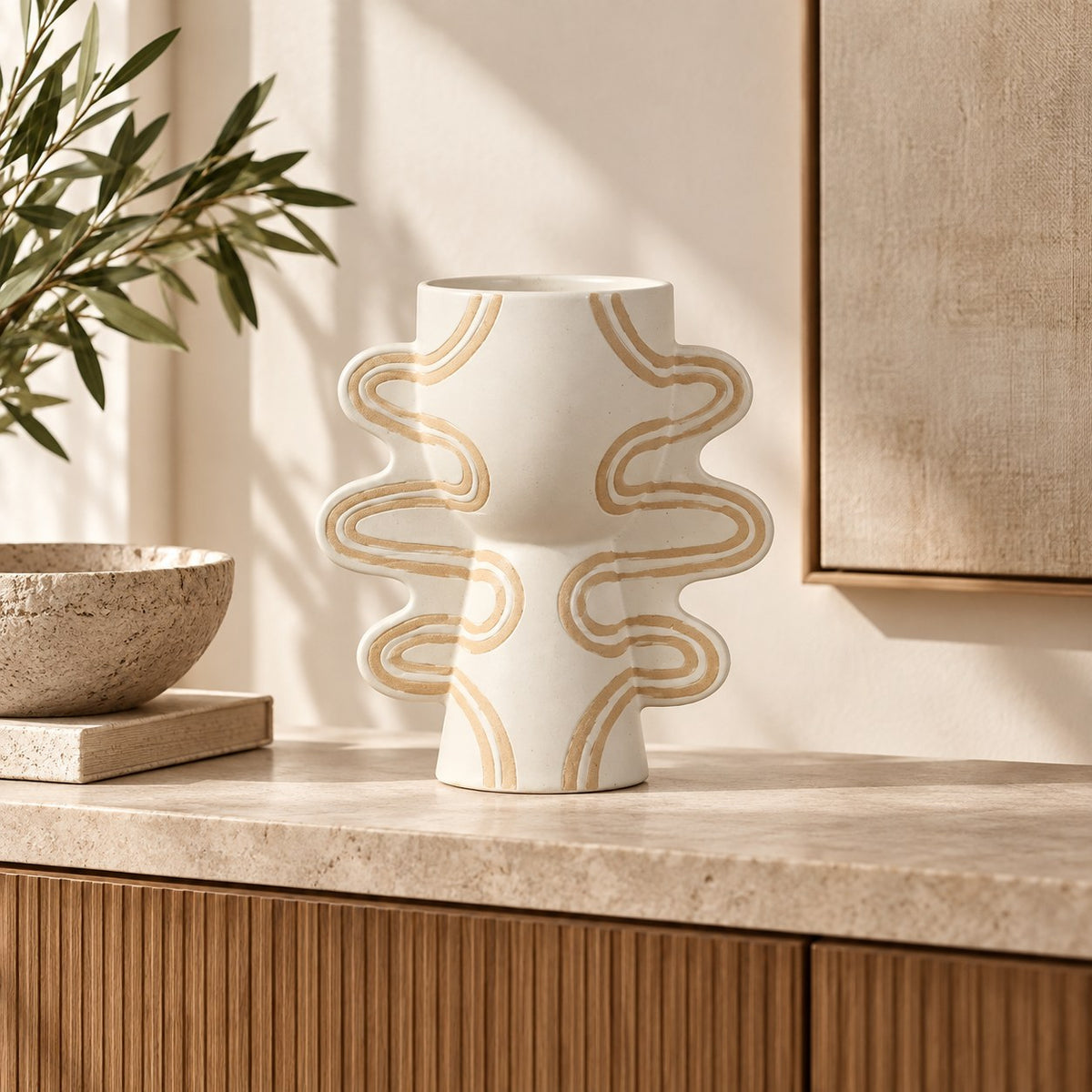 Leather Gallery Sirocco Sculptural Vase, featuring a white ceramic finish with flowing gold wave detailing in a warm minimalist interior.
