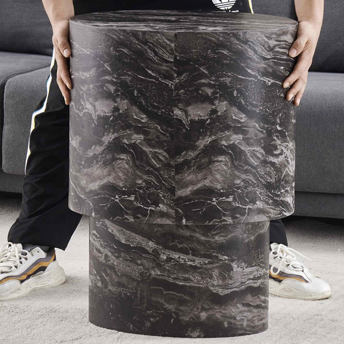 Gallery Everyday Callaway Coffee Table Set of 2, showing one cylindrical marble-look table being held in a living room.