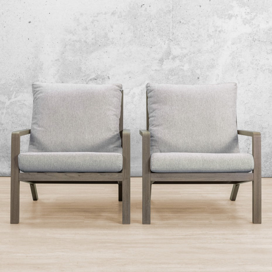 Pair of weathered grey wood outdoor armchairs with light grey cushions, front view in studio