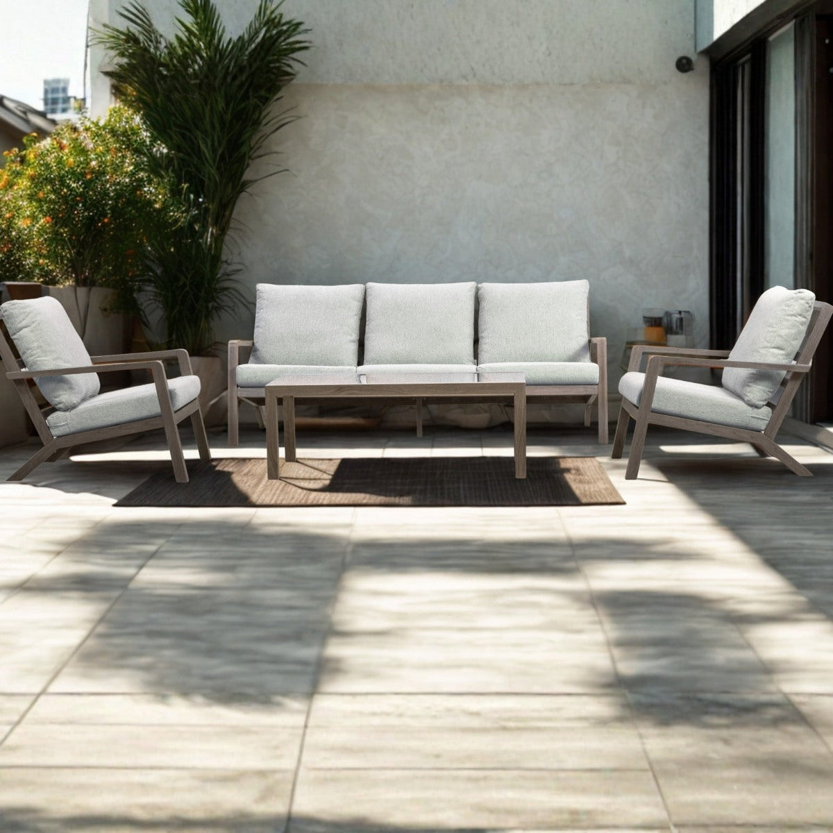 Weathered-wood outdoor lounge suite with grey cushions and a coffee table on a sunny tiled terrace