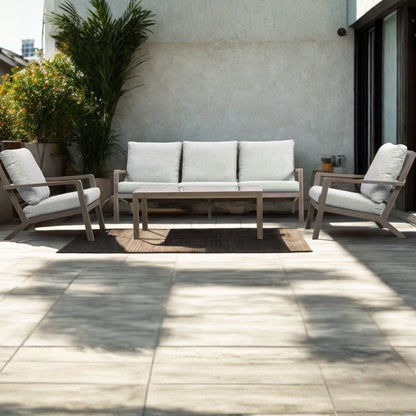 Weathered-wood outdoor lounge suite with grey cushions and a coffee table on a sunny tiled terrace