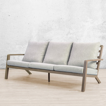 Three-seater outdoor sofa in weathered grey wood with soft grey cushions, shown in studio