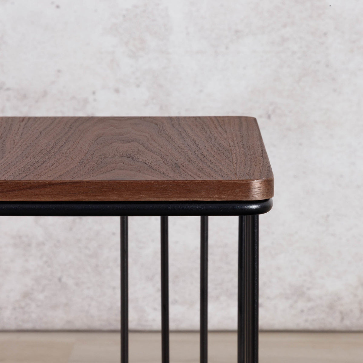 Close-up of the Gallery Everyday Camila Side Table in Walnut, showing the rounded wood-grain tabletop and black metal slatted base.