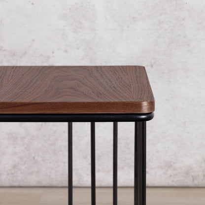 Close-up of the Gallery Everyday Camila Side Table in Walnut, showing the rounded wood-grain tabletop and black metal slatted base.